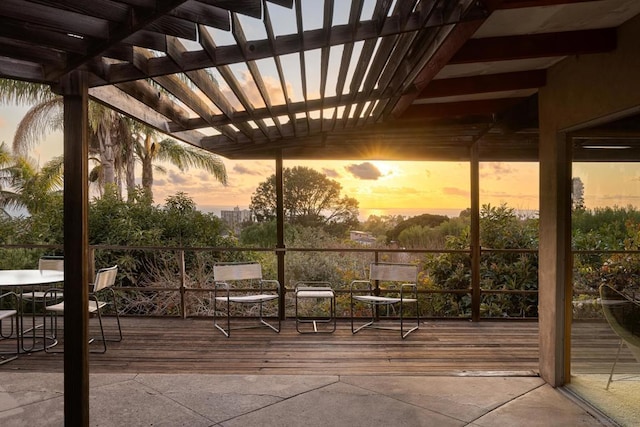 patio terrace at dusk featuring a wooden deck and a pergola