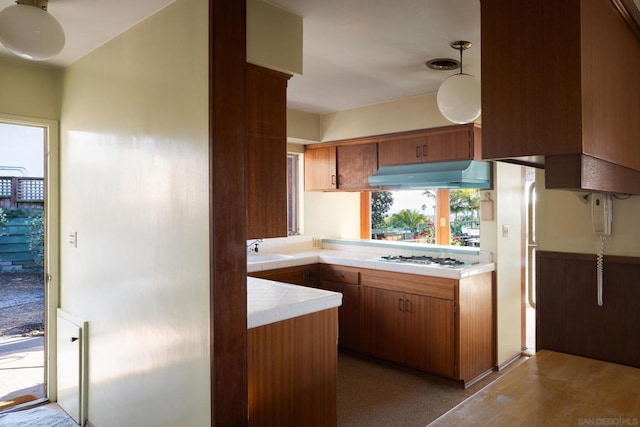 kitchen with sink, ventilation hood, hanging light fixtures, gas cooktop, and kitchen peninsula