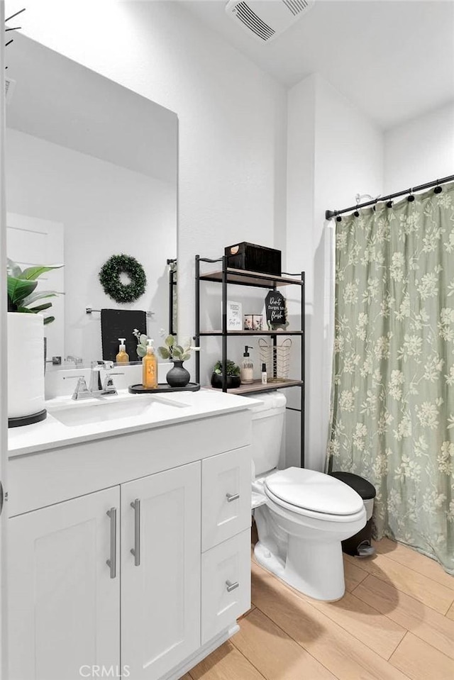 bathroom with vanity, hardwood / wood-style floors, toilet, and walk in shower