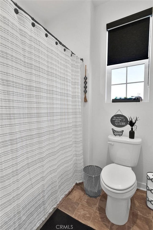 bathroom featuring tile patterned flooring, walk in shower, and toilet