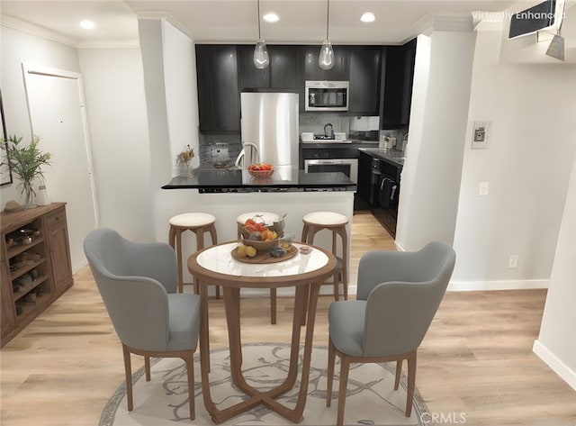 kitchen featuring stainless steel appliances, kitchen peninsula, hanging light fixtures, and light wood-type flooring