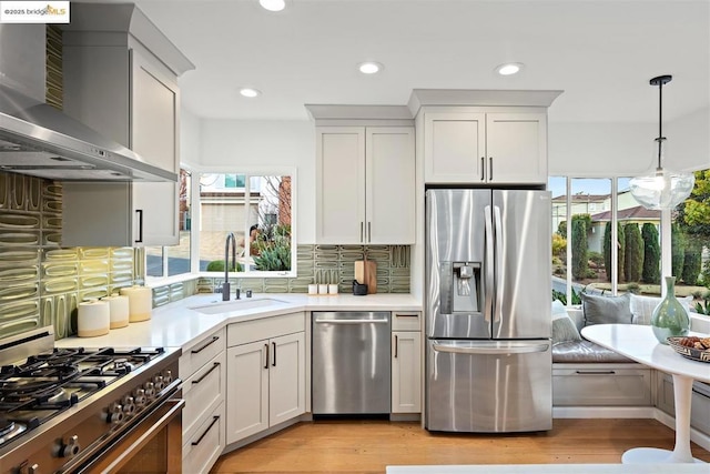 kitchen with sink, white cabinets, breakfast area, stainless steel appliances, and wall chimney exhaust hood