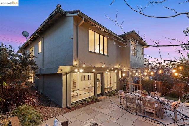 back house at dusk featuring a patio area