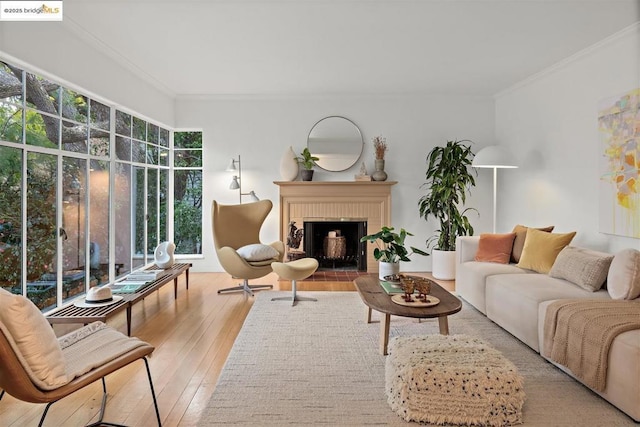 living room with a brick fireplace, light hardwood / wood-style flooring, and ornamental molding