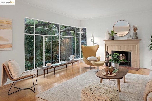 sitting room with crown molding, wood-type flooring, and a brick fireplace