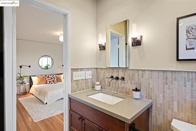 bathroom with vanity, wood-type flooring, tile walls, and toilet