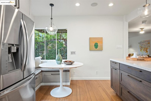 kitchen featuring breakfast area, pendant lighting, light hardwood / wood-style floors, and stainless steel refrigerator with ice dispenser