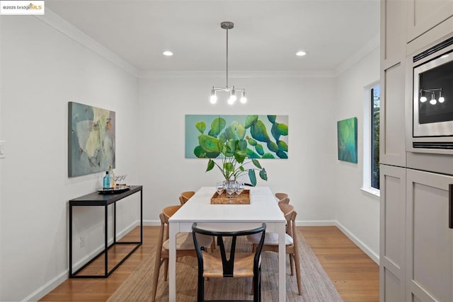 dining space featuring crown molding, a chandelier, and light hardwood / wood-style flooring