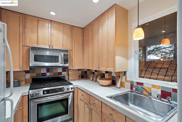 kitchen with stainless steel appliances, tasteful backsplash, sink, and tile counters