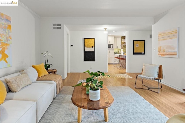 living room featuring ornamental molding and light wood-type flooring