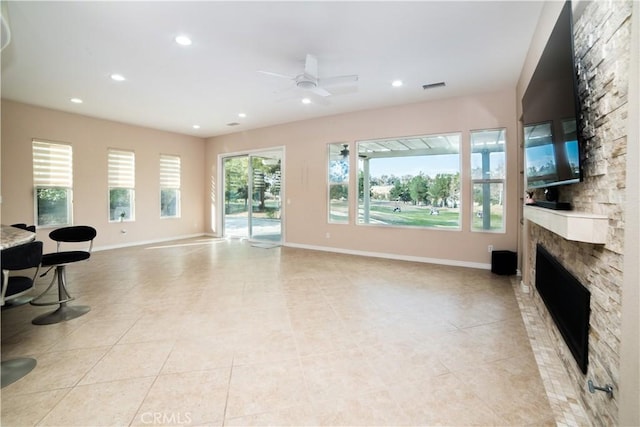 tiled living room with ceiling fan and a fireplace