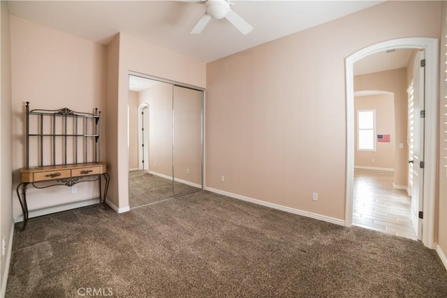 unfurnished bedroom featuring ceiling fan, dark carpet, and a closet