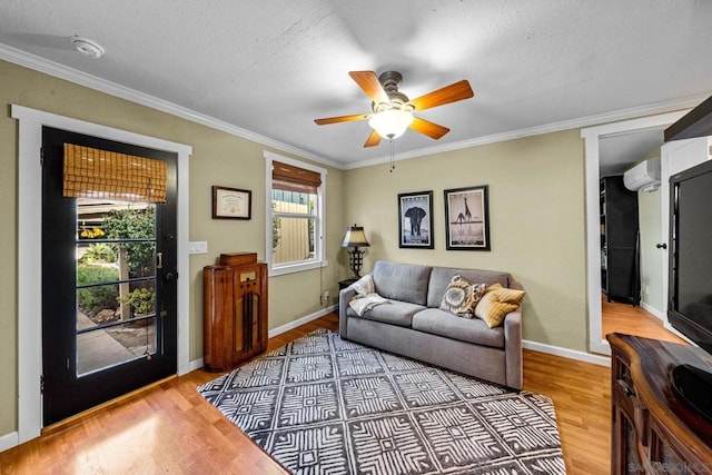 living room featuring crown molding, ceiling fan, a wall mounted AC, and light hardwood / wood-style flooring