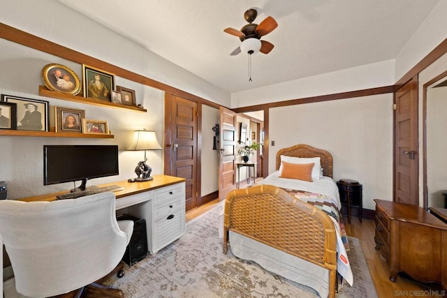 bedroom featuring ceiling fan, built in desk, and light wood-type flooring