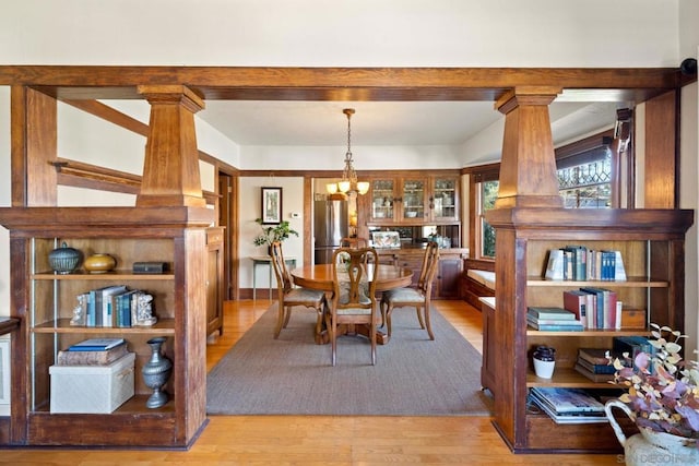 dining space featuring decorative columns, light hardwood / wood-style floors, and a chandelier