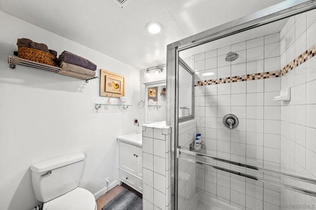 bathroom with vanity, a shower with shower door, and toilet