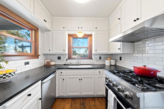 kitchen with appliances with stainless steel finishes, tasteful backsplash, sink, white cabinets, and dark hardwood / wood-style flooring