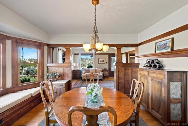 dining room with decorative columns, a notable chandelier, and light hardwood / wood-style floors