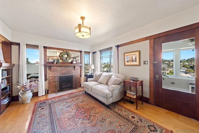 living room with a brick fireplace, a wealth of natural light, and light hardwood / wood-style floors