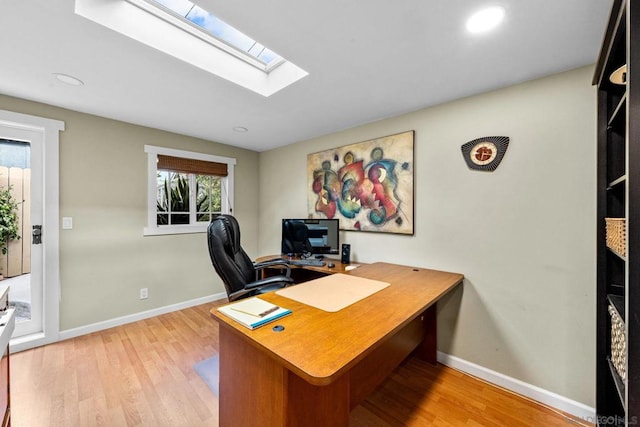 home office with a skylight and light hardwood / wood-style flooring