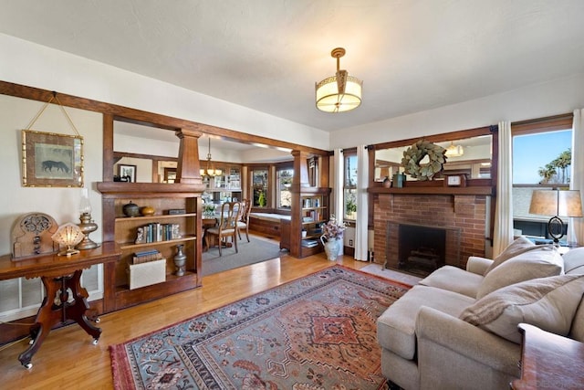 living room with plenty of natural light, light hardwood / wood-style floors, and a brick fireplace