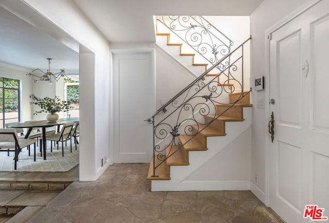 stairway featuring a notable chandelier