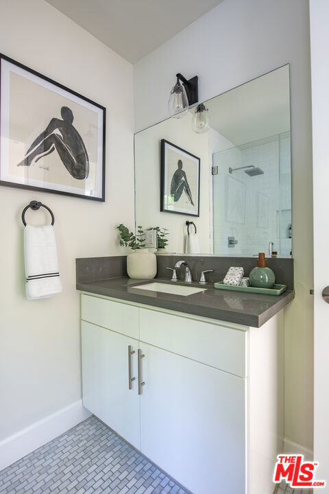 bathroom with vanity, a tile shower, and tile patterned floors