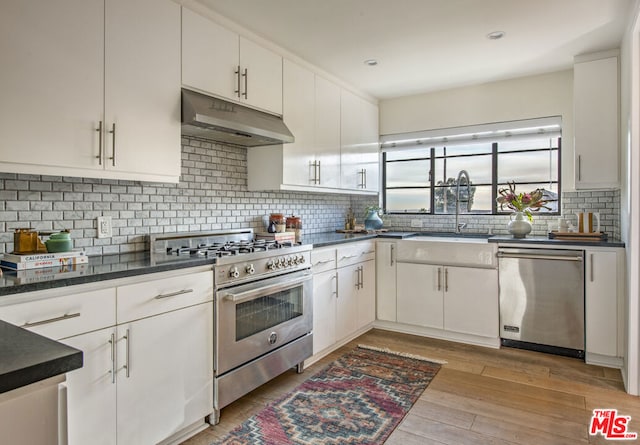 kitchen featuring sink, tasteful backsplash, light hardwood / wood-style flooring, appliances with stainless steel finishes, and white cabinets