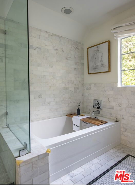 bathroom featuring tiled tub, lofted ceiling, tile walls, and tile patterned floors