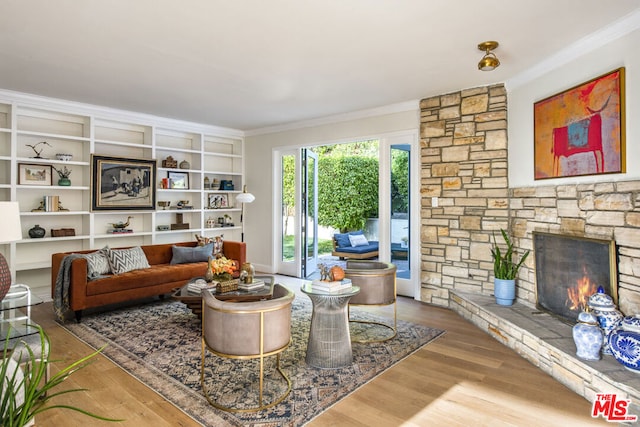 living room featuring wood-type flooring, ornamental molding, and a fireplace