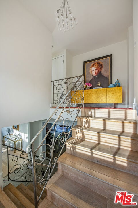 staircase with vaulted ceiling and a notable chandelier