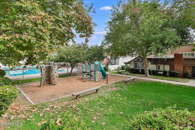 view of playground featuring a community pool and a lawn