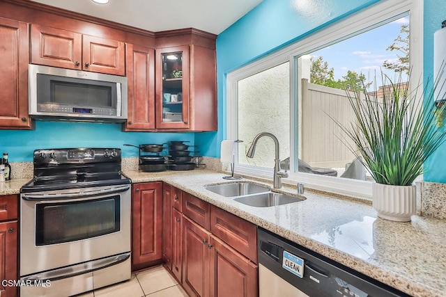 kitchen featuring light stone counters, stainless steel appliances, light tile patterned flooring, and sink