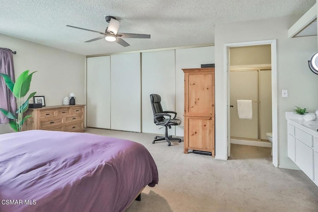 bedroom with ensuite bath, light colored carpet, ceiling fan, a textured ceiling, and a closet