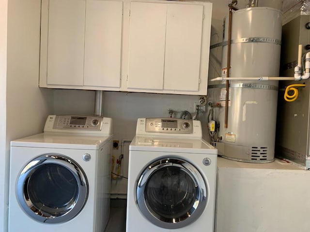 clothes washing area with strapped water heater, cabinets, and washer and dryer