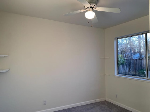 empty room with ceiling fan and dark carpet