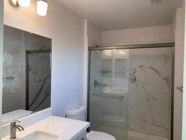 bathroom with walk in shower, vanity, and toilet