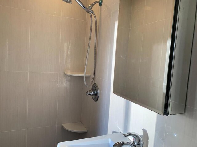 bathroom with tile walls, sink, and tiled shower