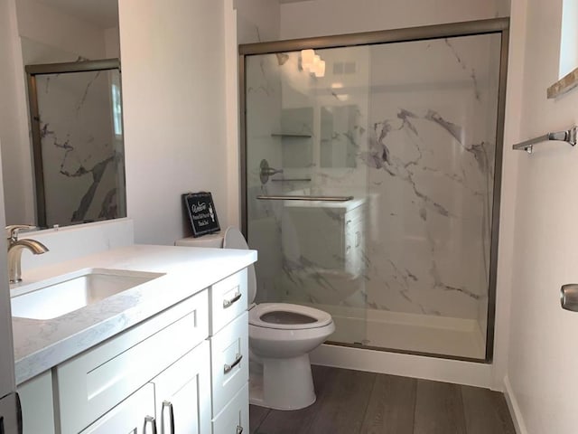 bathroom featuring vanity, hardwood / wood-style floors, toilet, and walk in shower