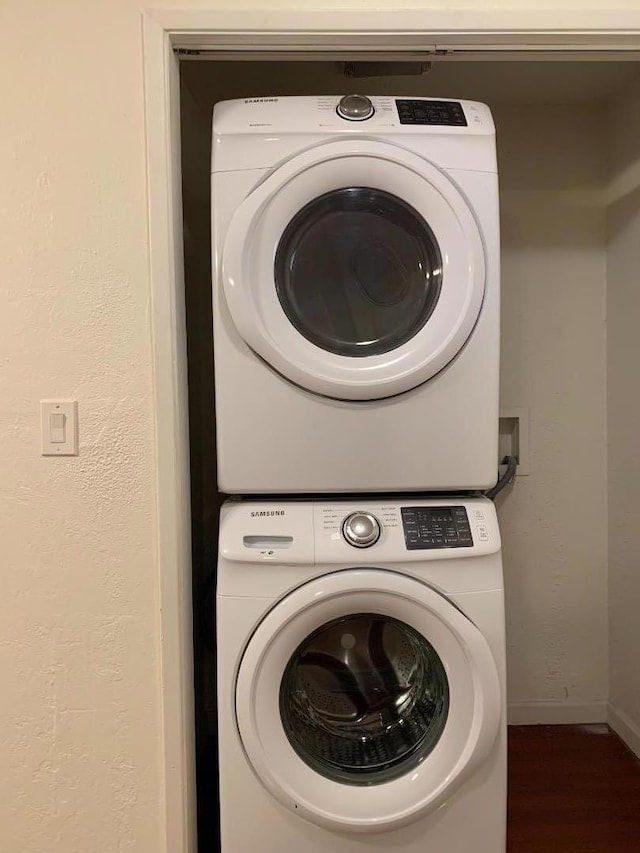 washroom with dark hardwood / wood-style flooring and stacked washer and dryer