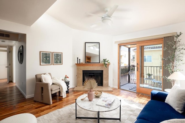 living room featuring hardwood / wood-style flooring, a premium fireplace, and ceiling fan