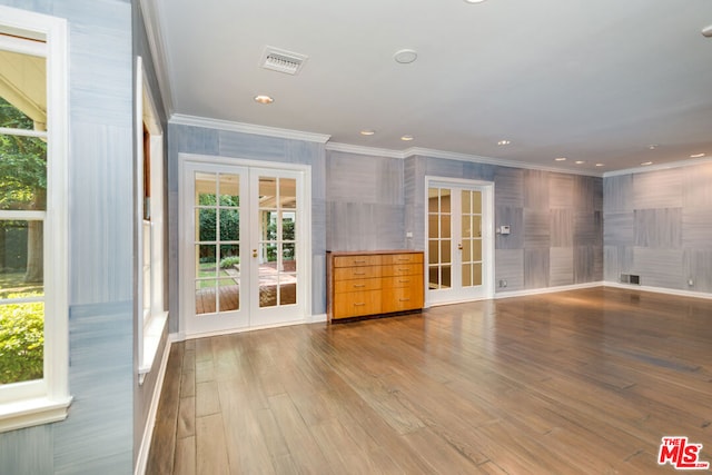 empty room with crown molding, light hardwood / wood-style flooring, and french doors