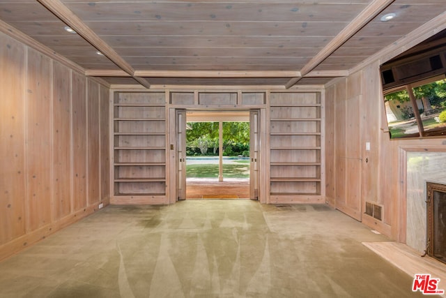 interior space featuring built in shelves, carpet flooring, wooden walls, and a fireplace