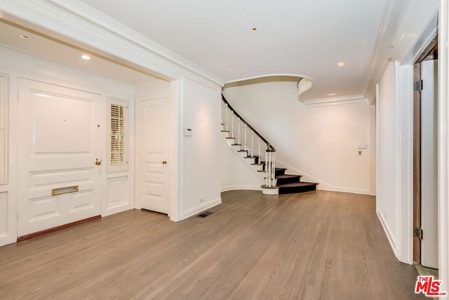 foyer featuring crown molding and light hardwood / wood-style floors