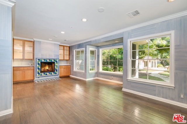 unfurnished living room featuring dark hardwood / wood-style flooring, crown molding, and a wealth of natural light