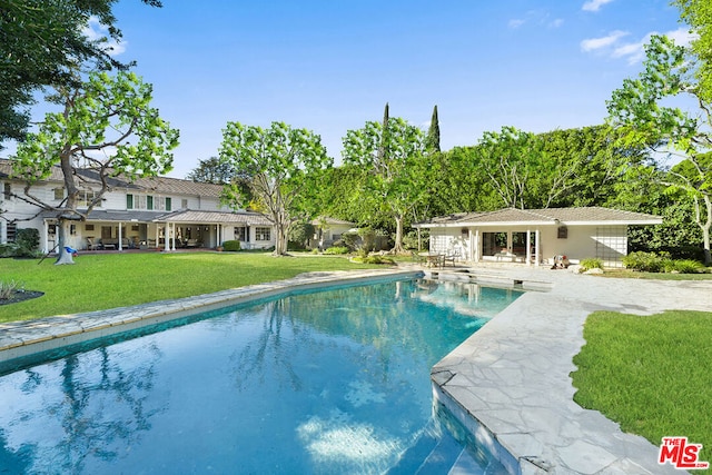 view of pool featuring a yard, an outbuilding, and a patio area