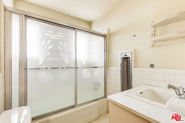 bathroom with enclosed tub / shower combo, tile walls, and vanity