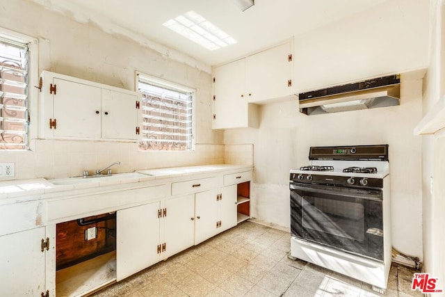 kitchen featuring tile countertops, sink, white cabinets, decorative backsplash, and white gas range oven