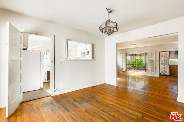 spare room with wood-type flooring and a chandelier