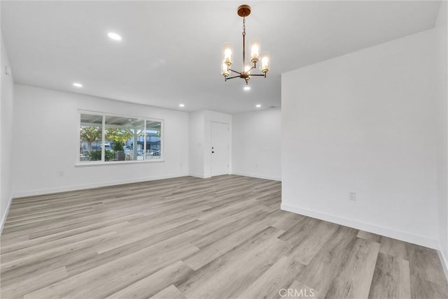 empty room with a notable chandelier and light hardwood / wood-style flooring